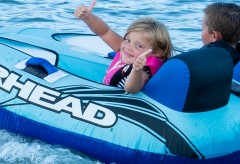 Girl giving a thumbs up on a tube in the water