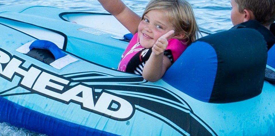 Girl giving a thumbs up on a tube in the water