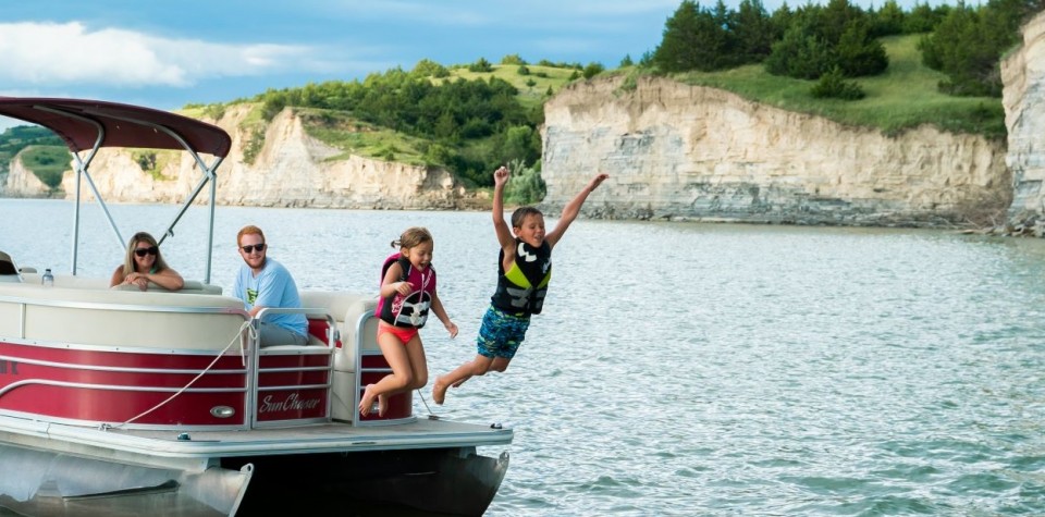 Kids jumping off a pontoon into the lake