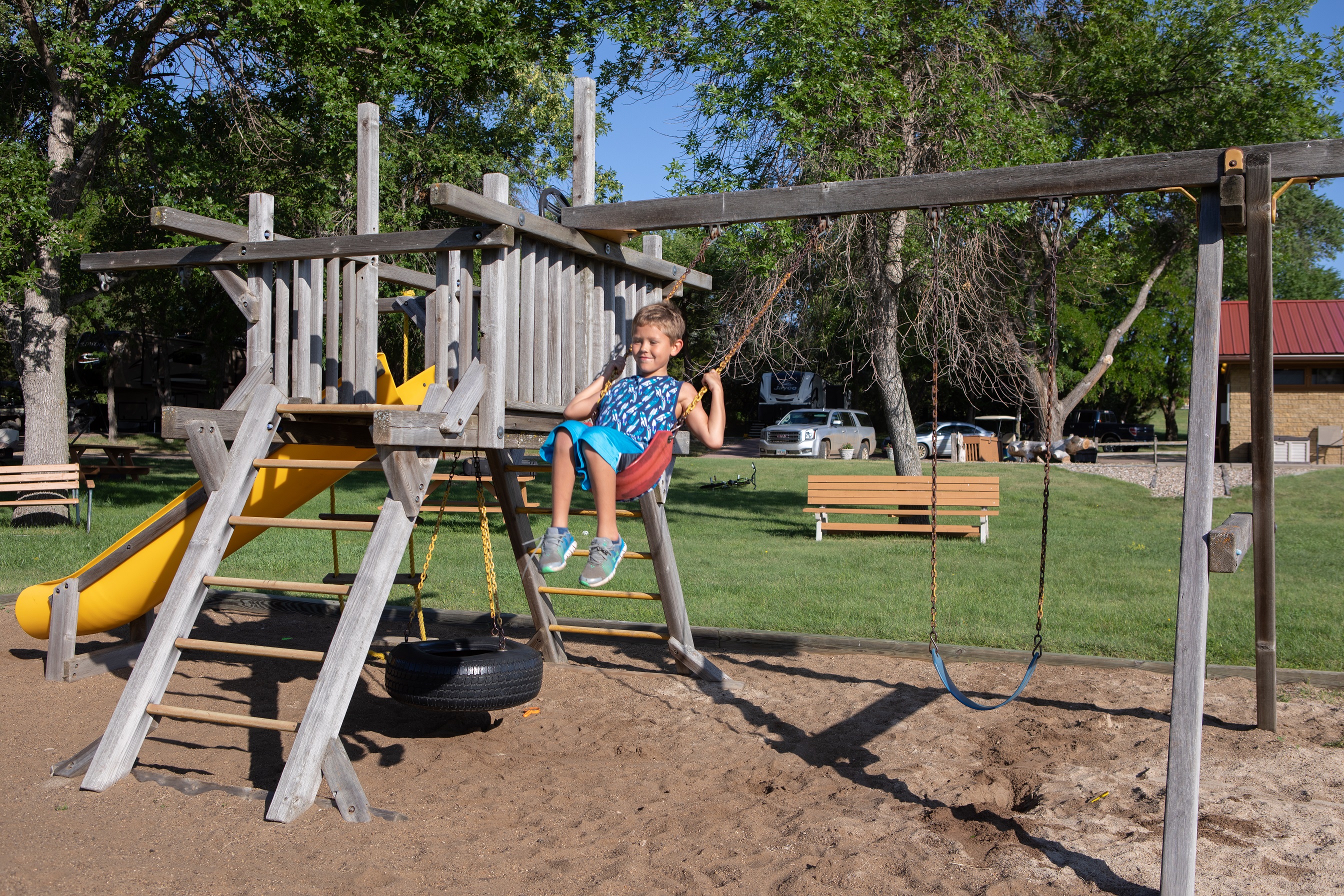 A child smiling on a swing set. 